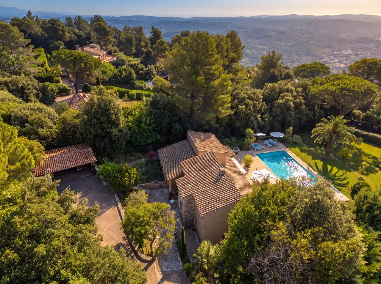 Vue aérienne de toits en tuiles, piscine et jardin dans la végétation