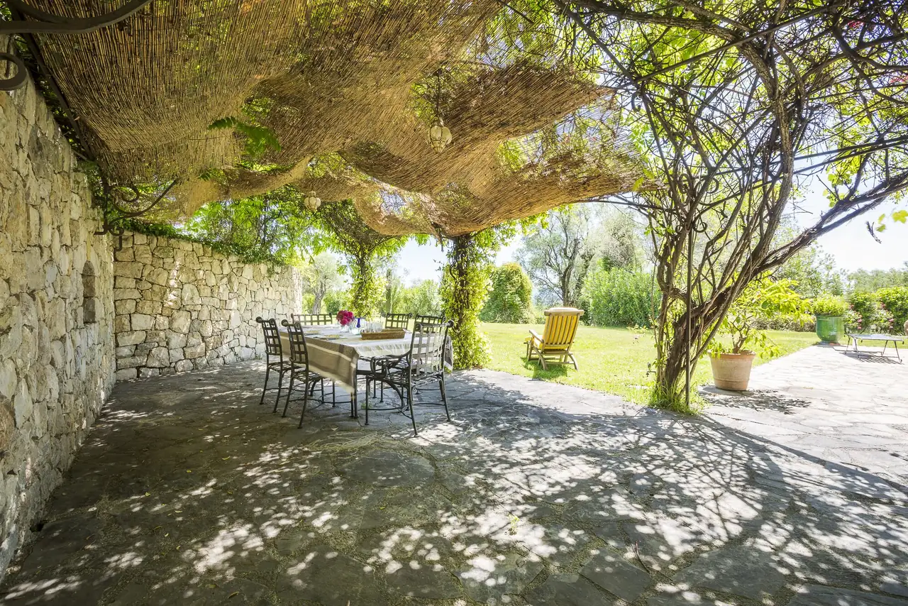 Table dressée sous une pergola de verdure, ouverte sur le jardin