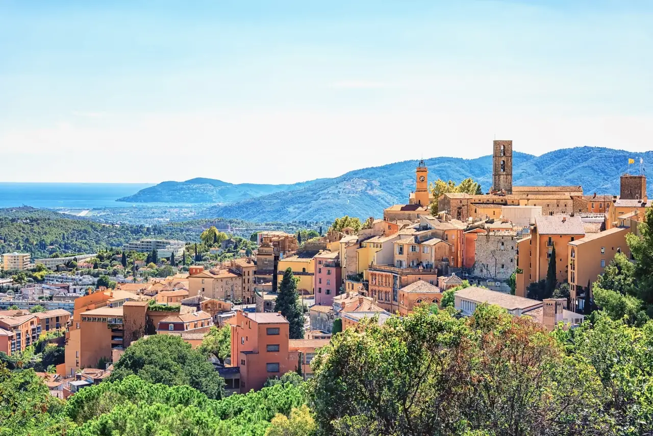La vieille ville de Grasse en balcon sur les collines, ses clochers dominant les toits de tuiles, la baie au loin