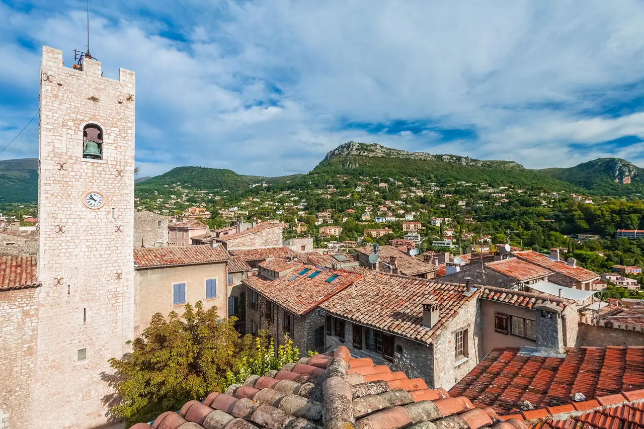 La tour de l'horloge de Vence et les toits de tuiles du vieux village, adossés aux baous boisés